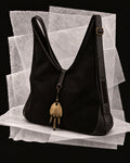 Andrea bag in Black with the Bronce amulet, a hand-finished bronze form with three suspended lines